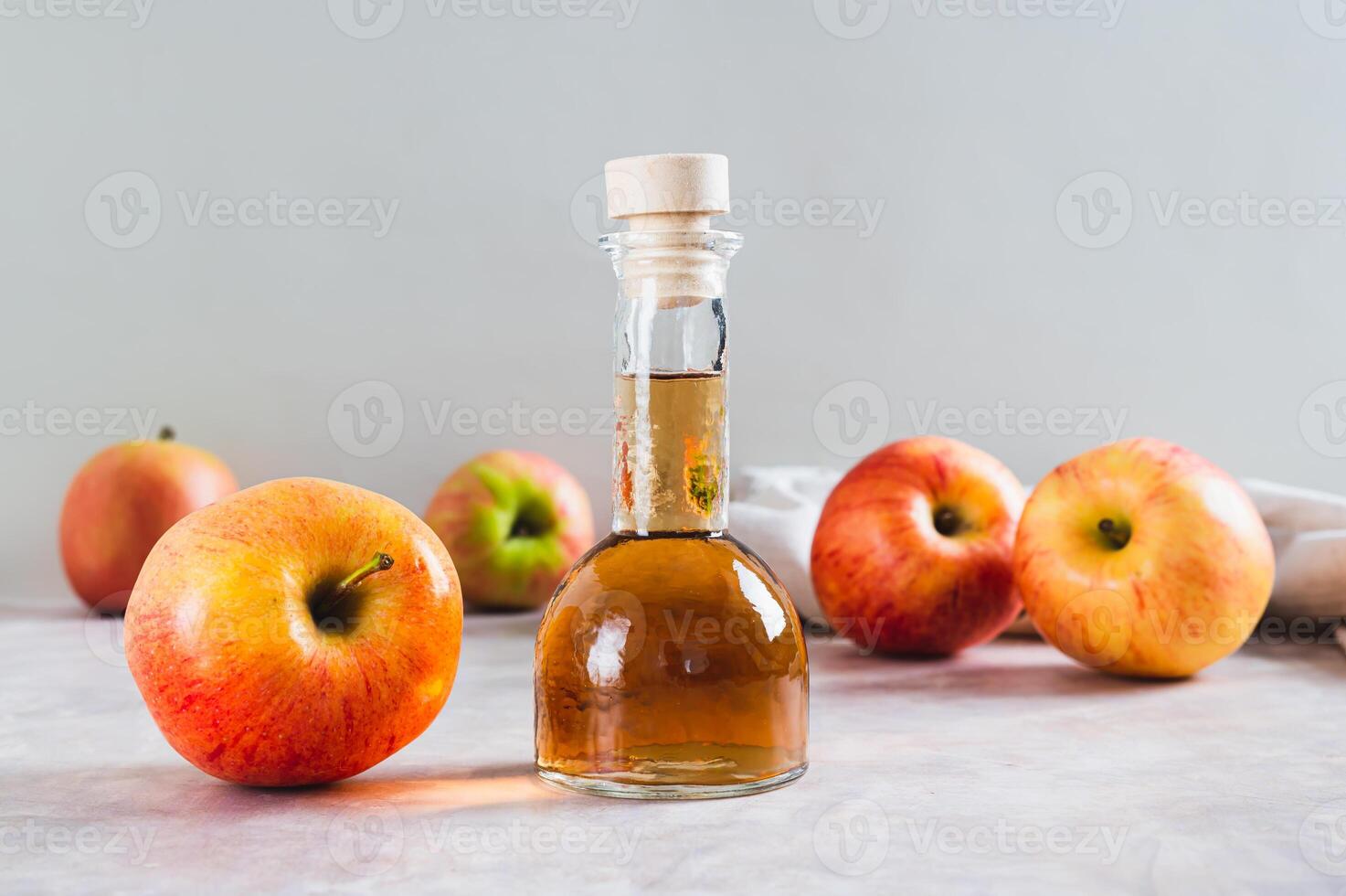 Apple cider vinegar in a bottle and fresh apples on the table photo