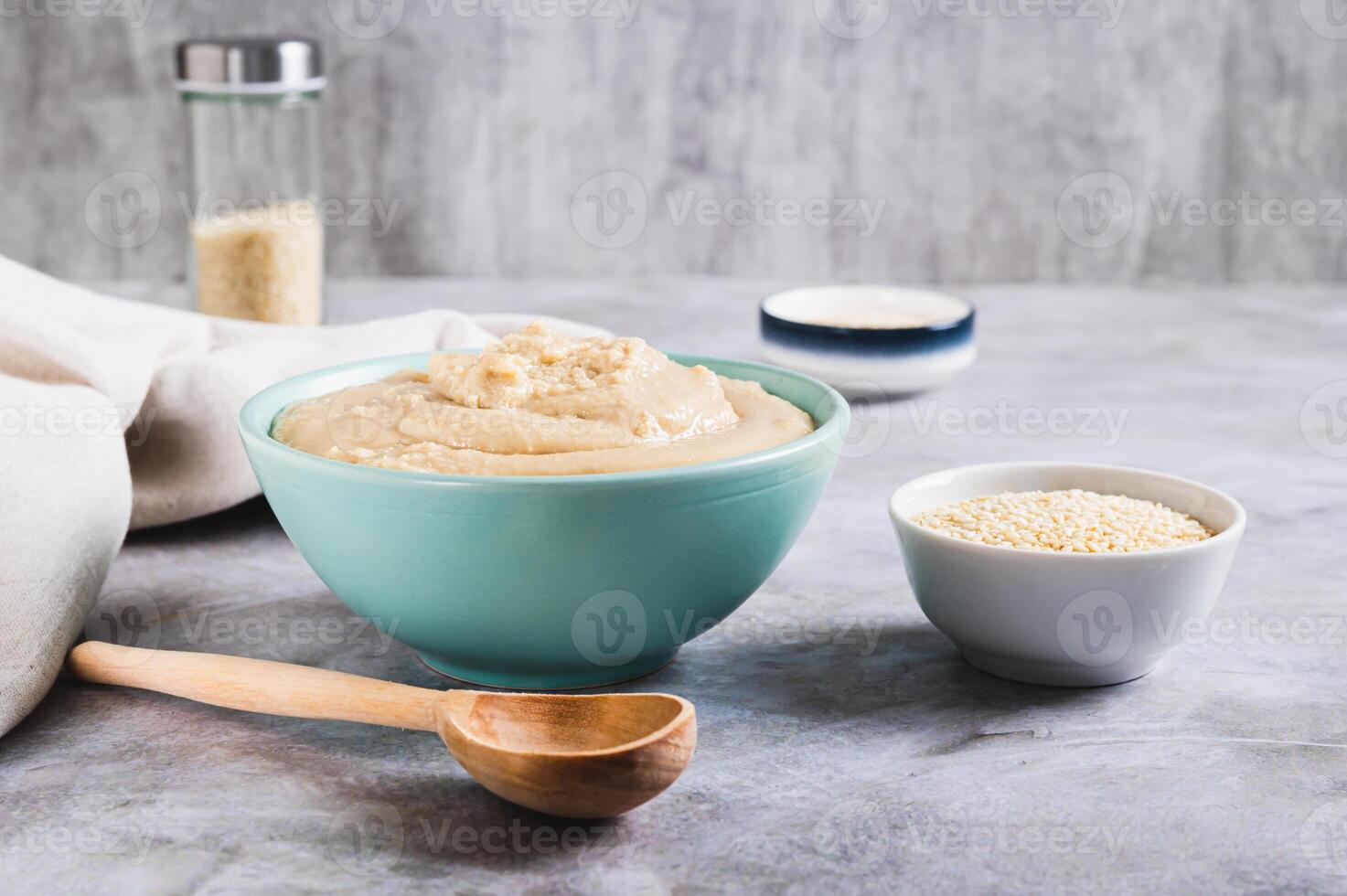 Sesame tahini in a bowl and sesame seeds in a bowl on the table photo