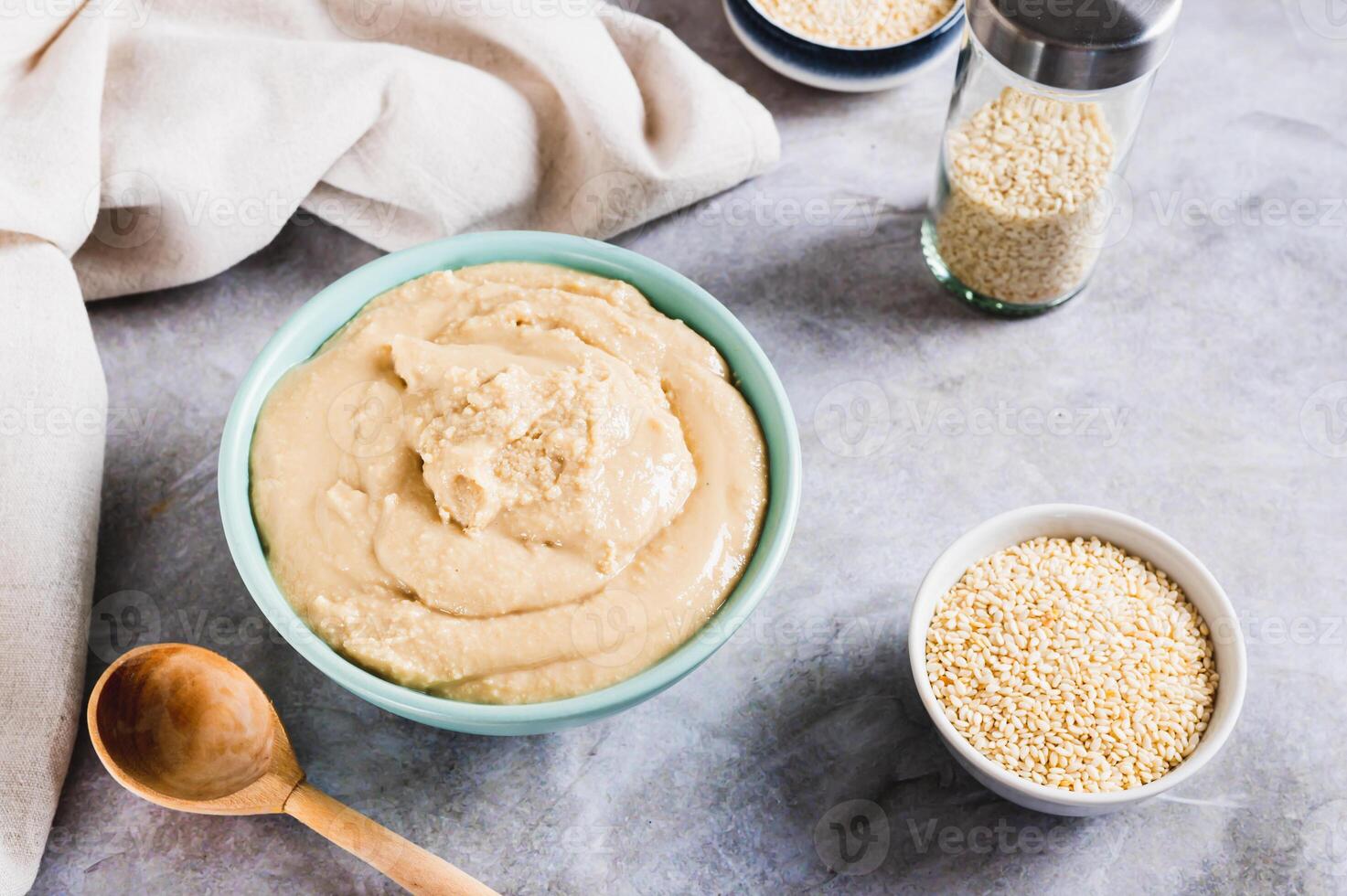 Homemade sesame tahini in bowl on grey table photo