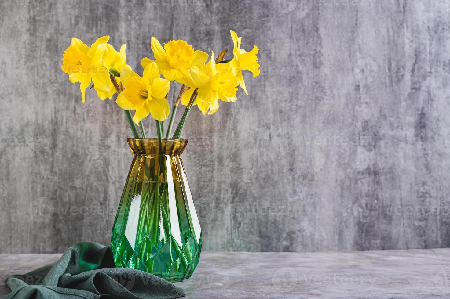 Fresh spring flowers yellow daffodils in vase on grey table photo