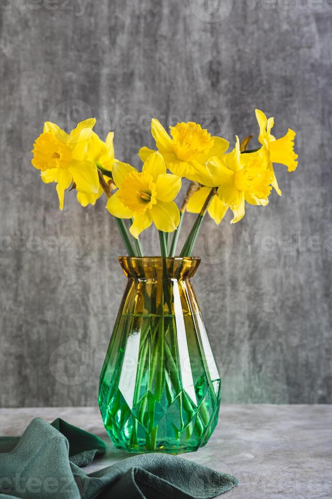 Fresh spring flowers yellow daffodils in vase on grey table vertical view photo