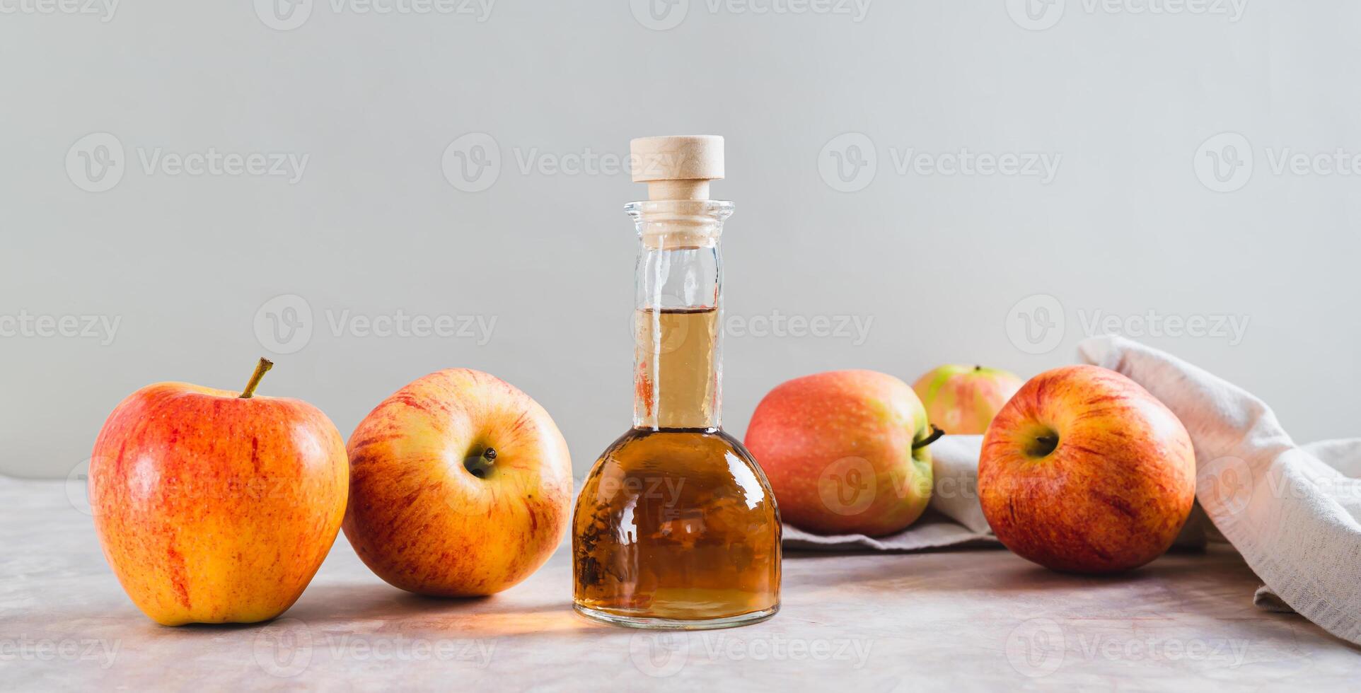 Apple cider vinegar in a bottle and fresh apples on the table web banner photo