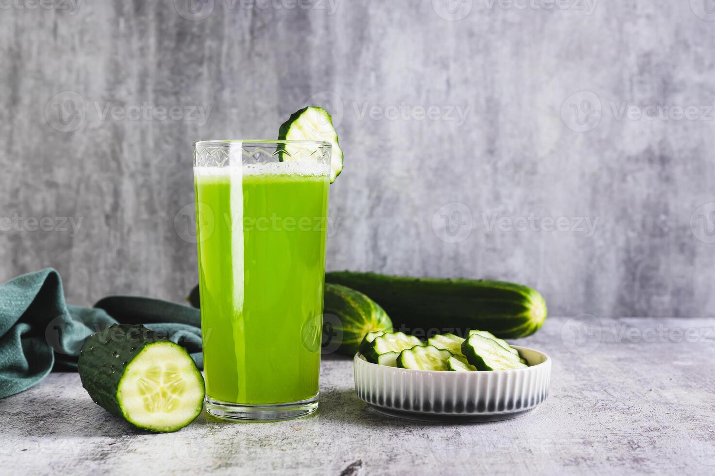 Fresh cucumber juice in a glass and cucumber pieces in a bowl on the table photo
