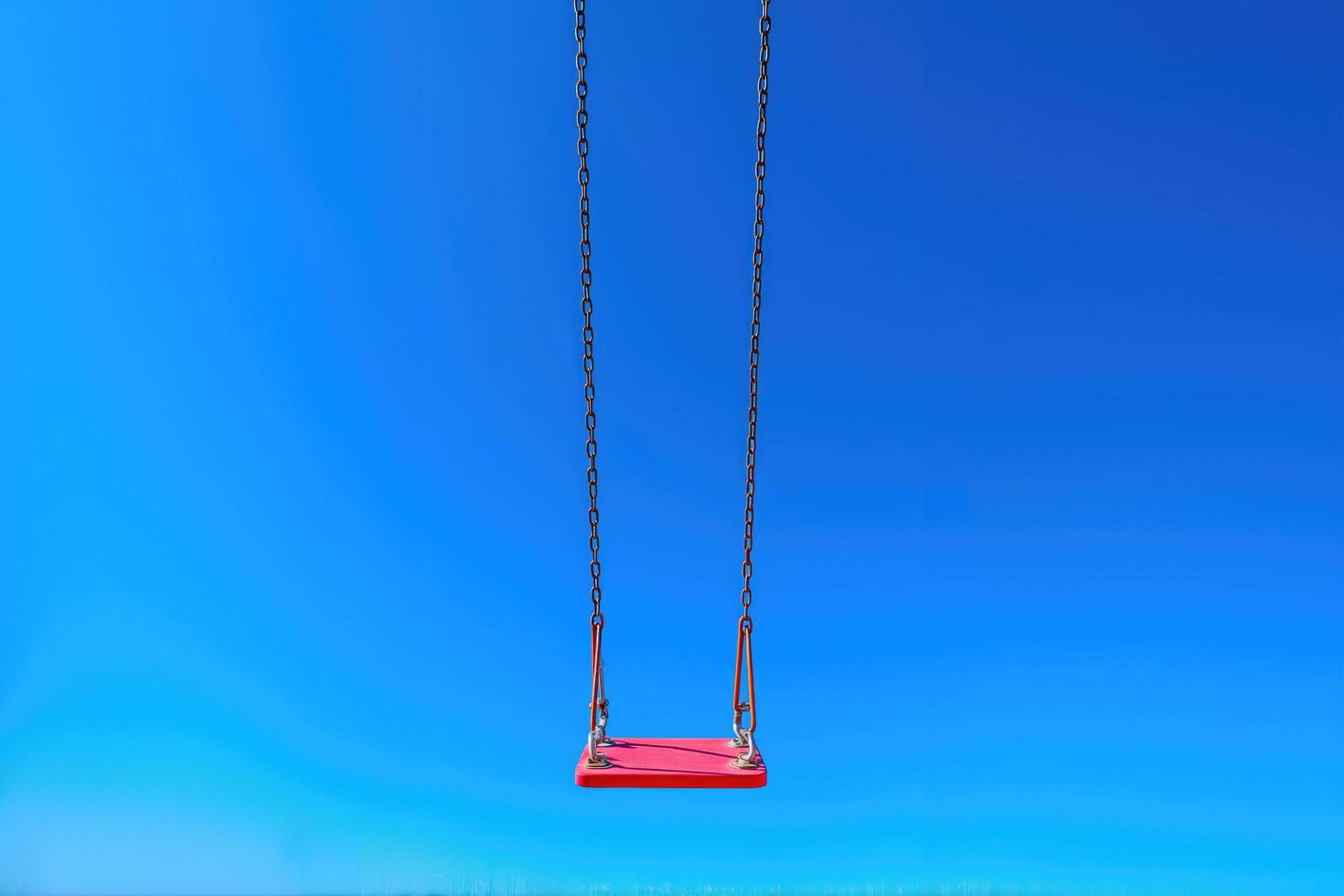 Red swing against a vibrant blue sky, symbolizing carefree joy. photo