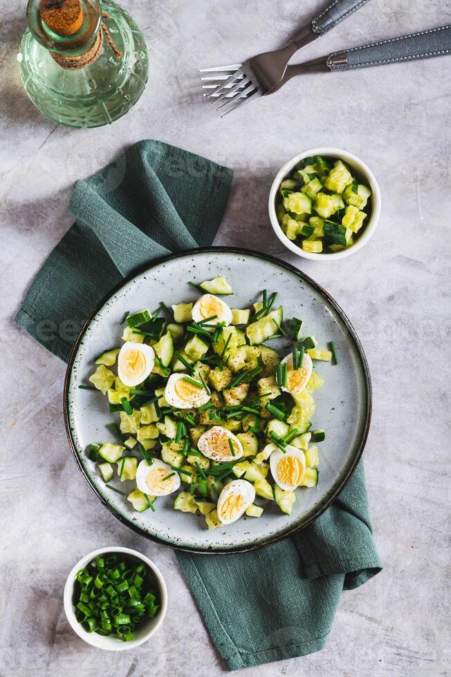 Appetizing mix of cucumbers, eggs and chives on a plate on the table top and vertical view photo