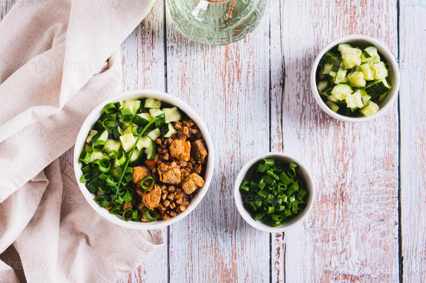 Buckwheat porridge with meat, cucumber and chives in a bowl on the table top view photo