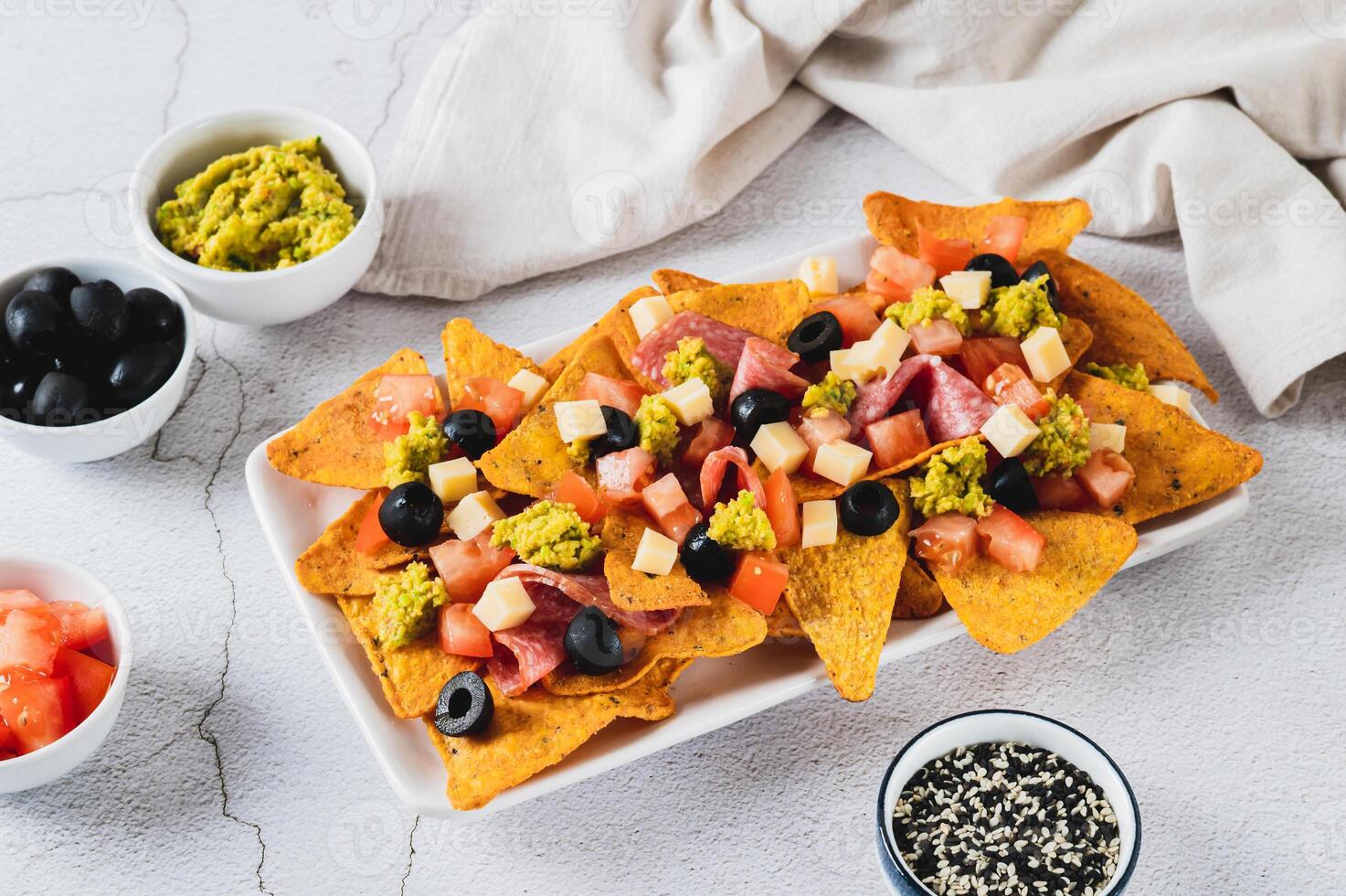 Appetizer plate with nachos, salami, cheese, tomato and black olives on the table photo