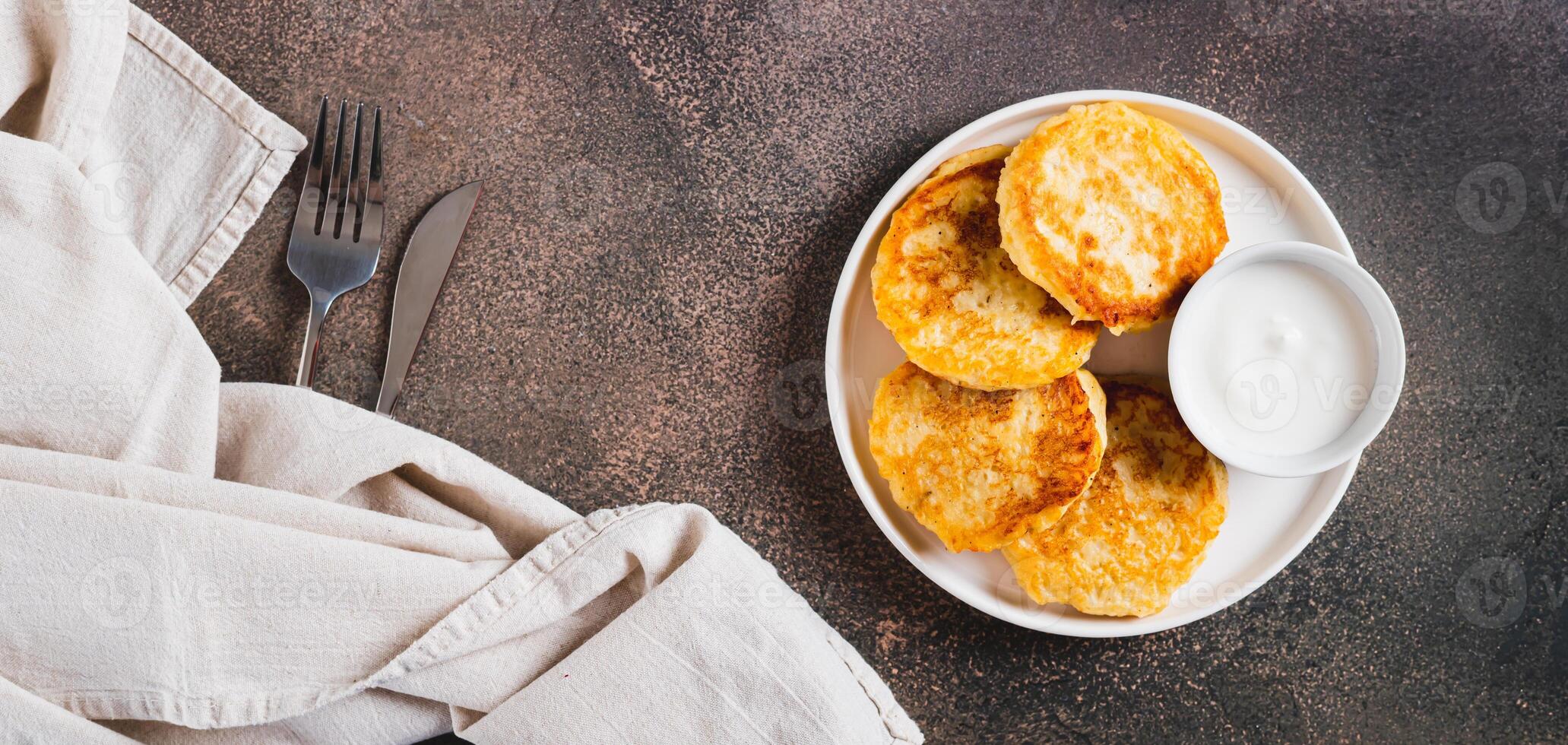 Appetizing potato fritters and sour cream on a plate on the table top view web banner photo