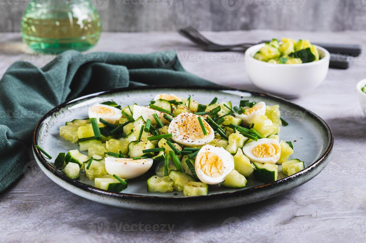 Fresh salad of cucumbers, quail eggs and green onions on a plate on the table photo