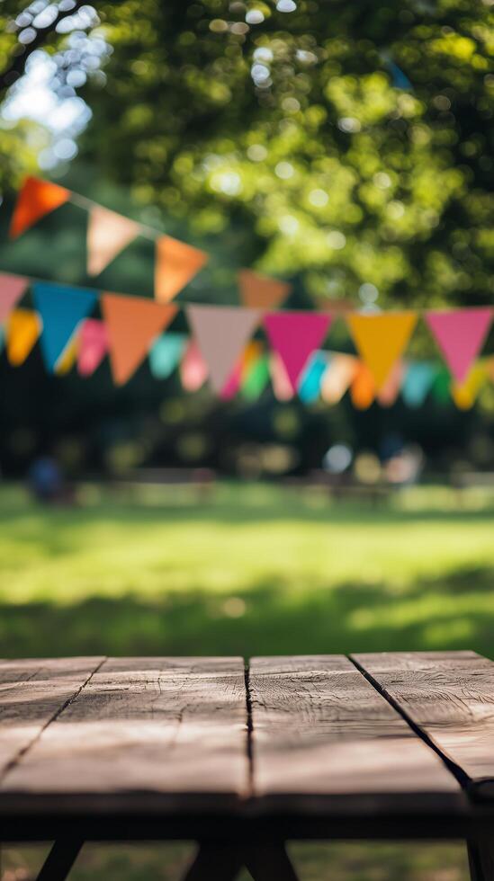 Rustic wooden table in foreground with colorful bunting blurred in background of sunny park. Summer celebration concept photo