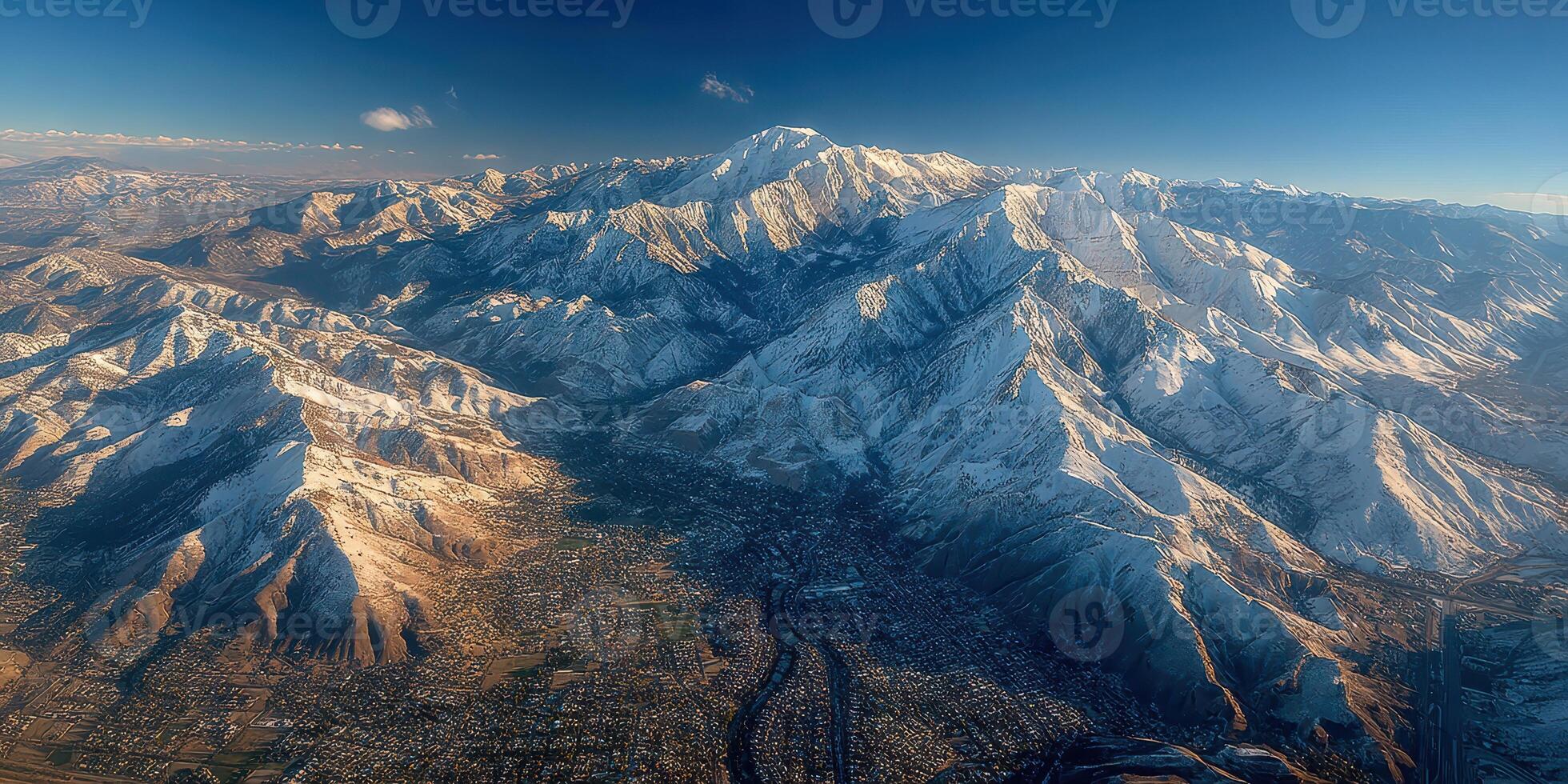 Mountain range covered in snow with a clear sky above a town during daylight photo