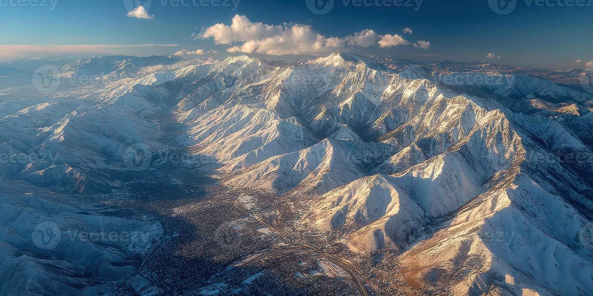 Snow-covered mountain range reveals serene valley at sunset in winter landscape photo
