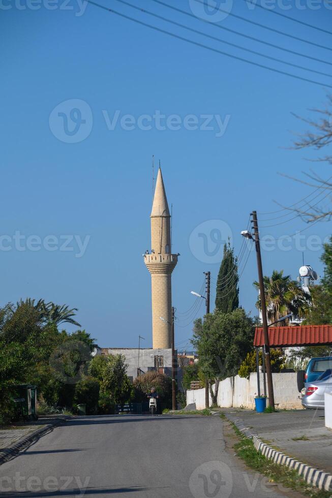 Towering minaret reaches towards the bright blue sky in a charming coastal town on a sunny day photo