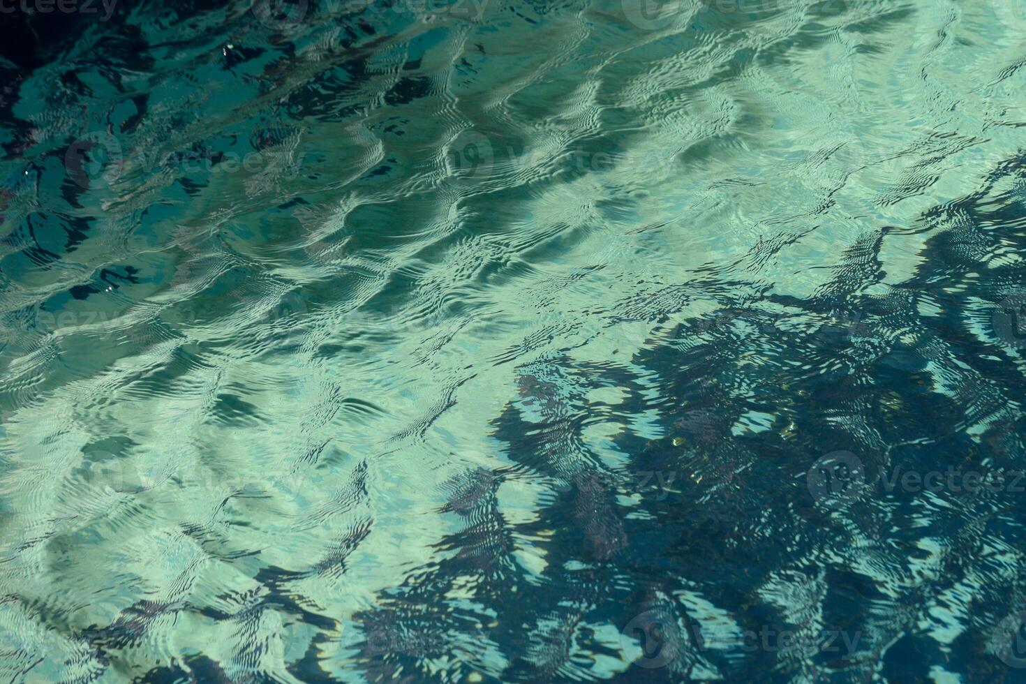 Reflections of tranquility dancing on the surface of clear blue waters at midday photo