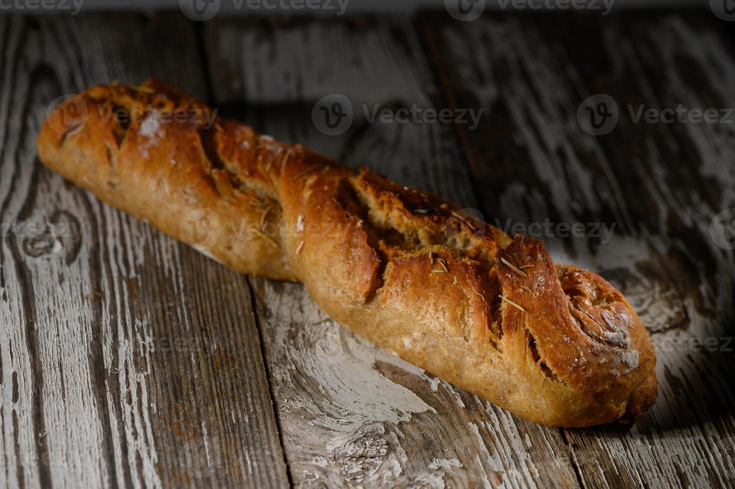 Freshly baked rustic bread loaf resting on an aged wooden table illuminated photo