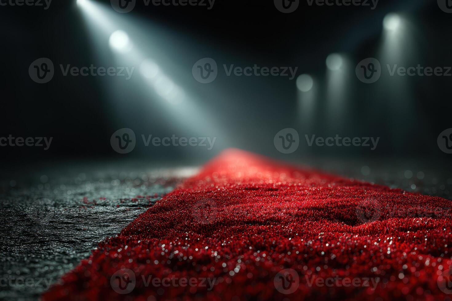 Shimmering red carpet leading to spotlight in a dimly lit venue during an evening event photo