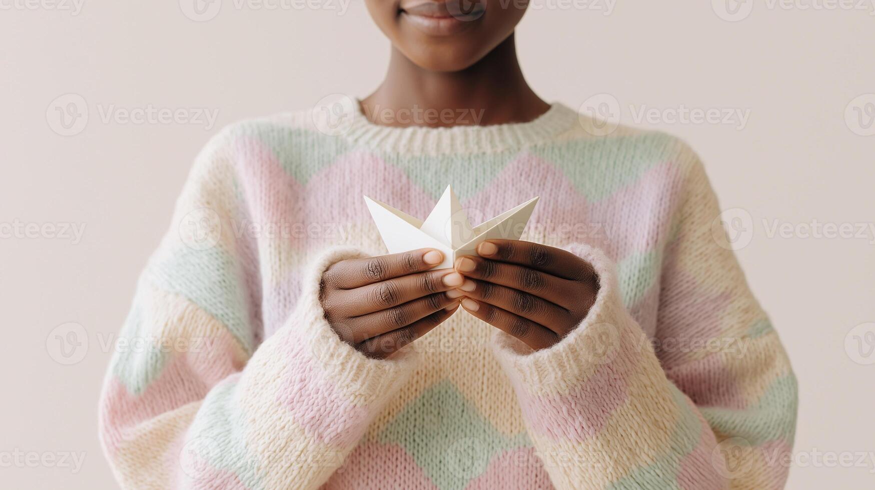 Calm young person in soft pastel sweater gently holding paper boat, symbolizing peace, mindfulness, emotional healing, and self-care. Light background emphasizes serenity and warmth. photo