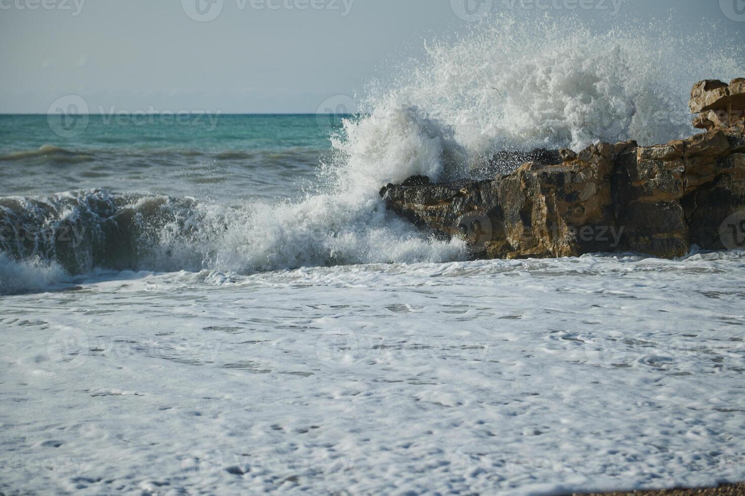 Majestic Ocean Waves Crashing Against Rocky Shoreline on a Sunny Day photo