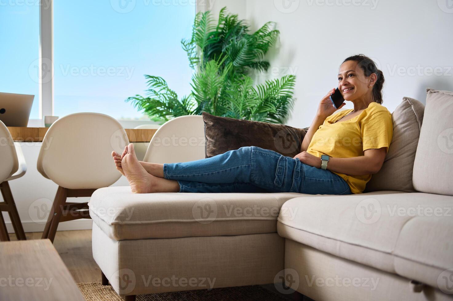 Relaxed Woman Telecommuting in Modern Home Living Room, Engaged in a Phone Call photo