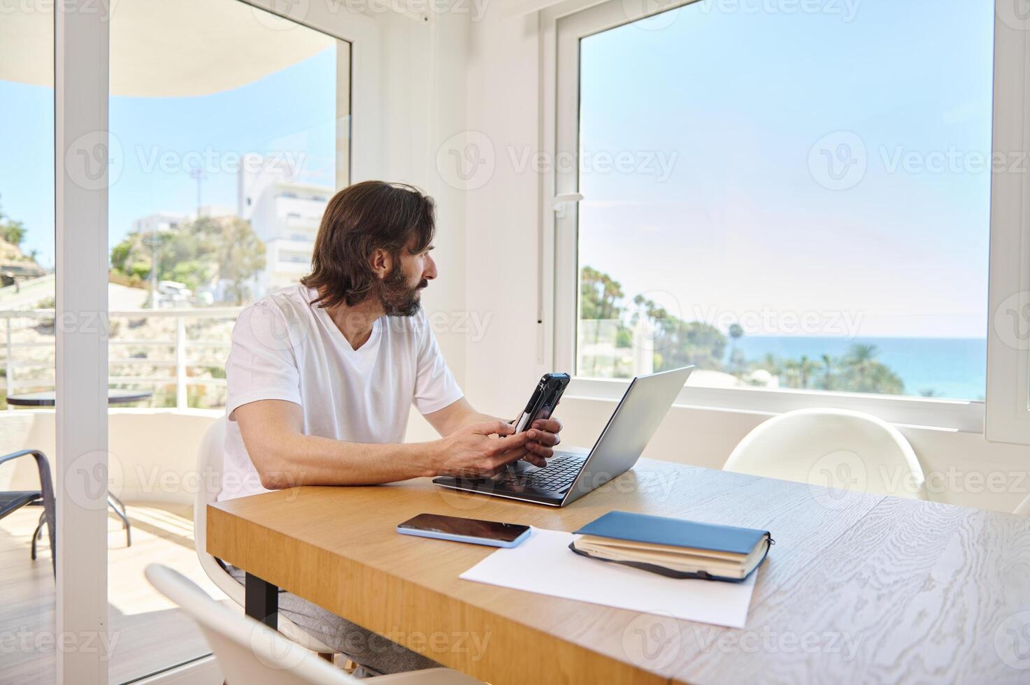 Man Telecommuting From a Modern Minimalist Home Office With Oceanview photo