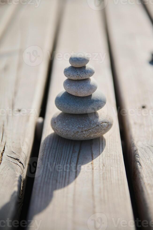 Balanced Stack of Smooth Pebbles on a Wooden Surface in Sunlight photo