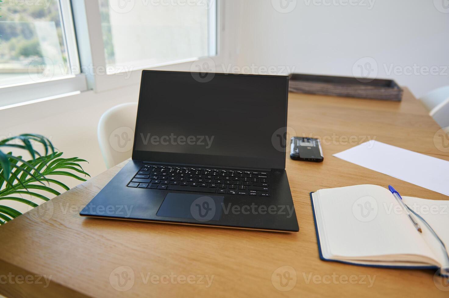 Modern Home Office Workspace With Black Laptop and Open Notebook photo