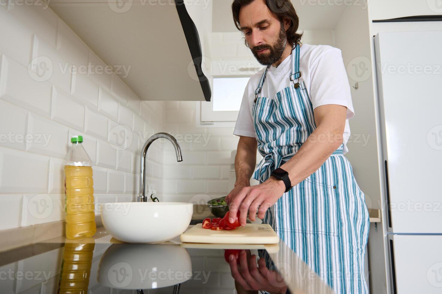 Man Preparing Healthy Meal in Modern Kitchen Wearing a Striped Apron photo