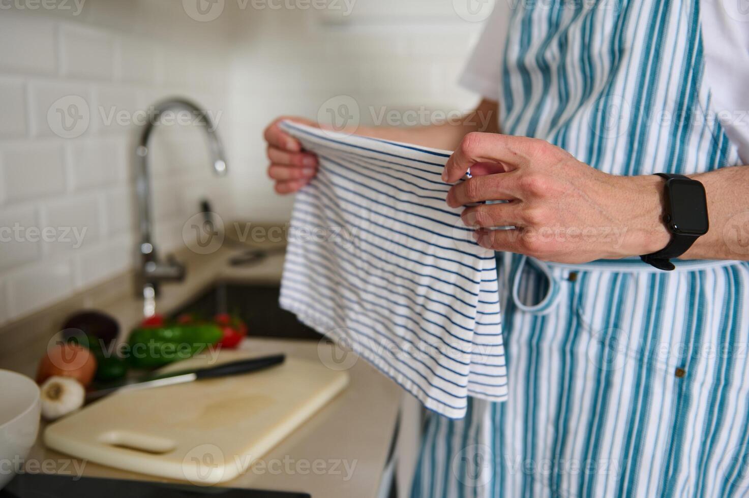 Man Preparing Salad in a Modern Kitchen Wearing Striped Blue Apron photo