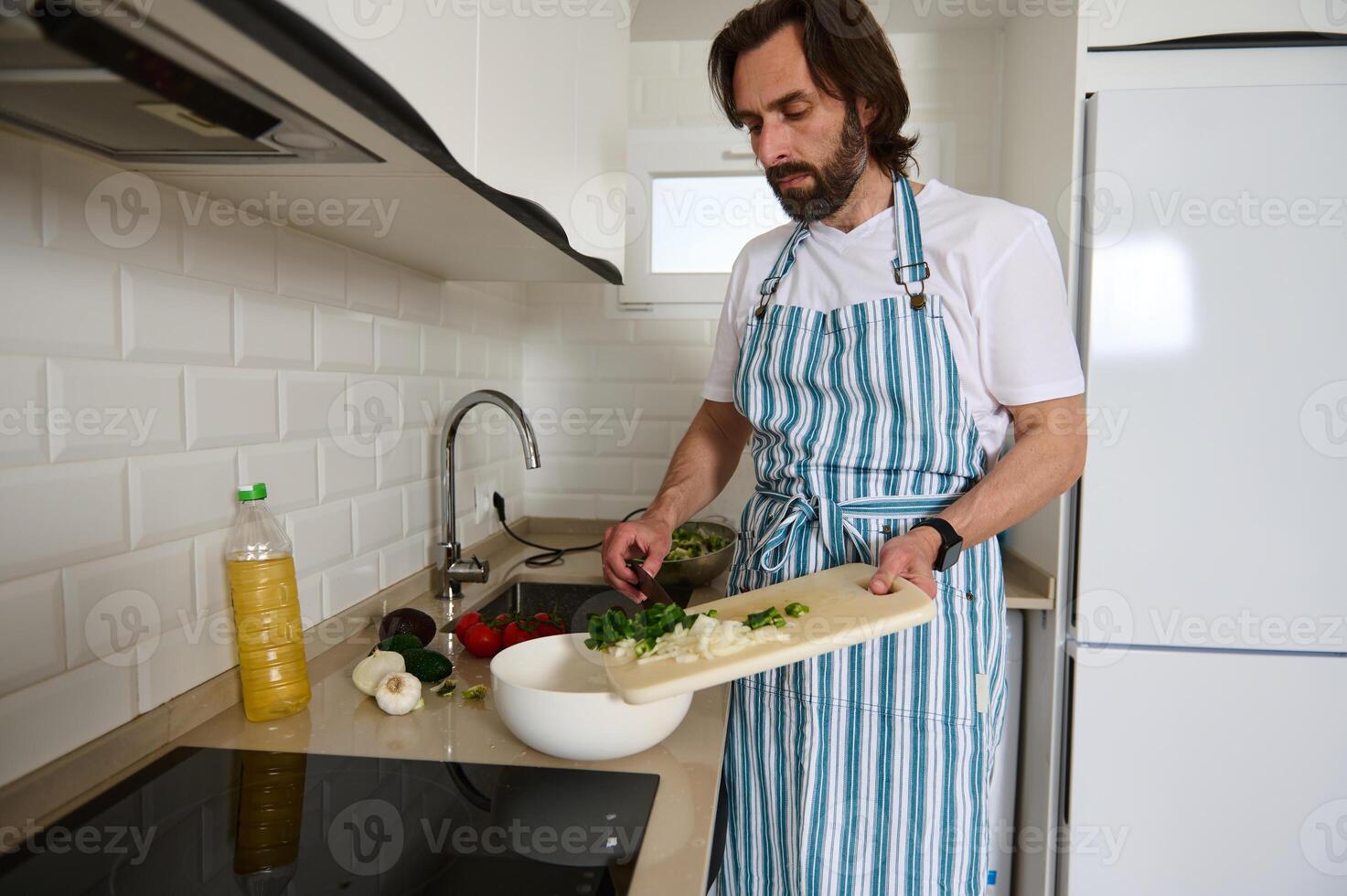 Man in Kitchen Preparing Healthy Salad Wearing a Striped Apron photo