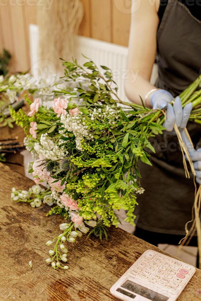 Florist arranging bouquet of flowers on wooden table, Mothers day photo