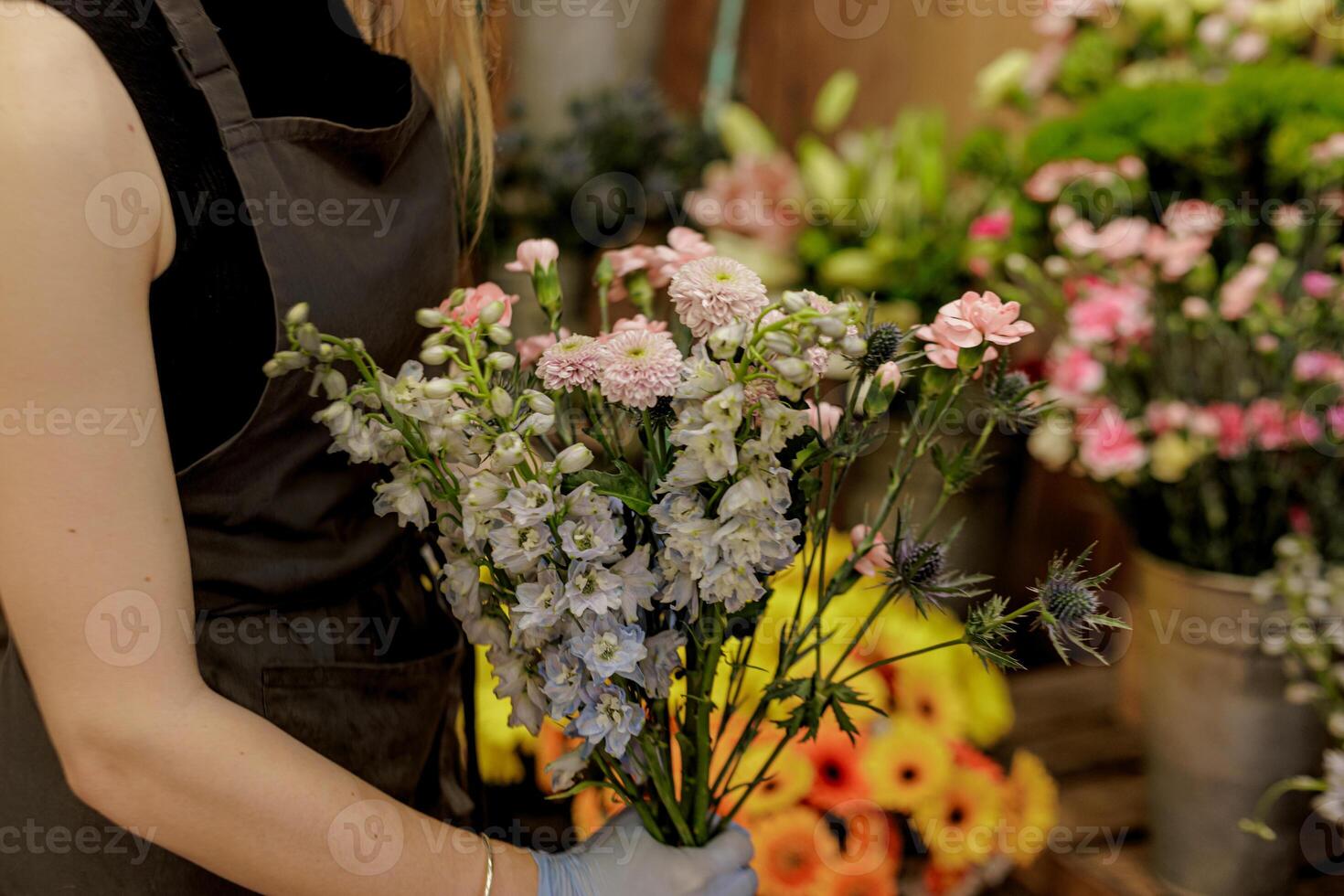 Florist arranging bouquet of larkspur and carnations in flower shop for Mothers day photo