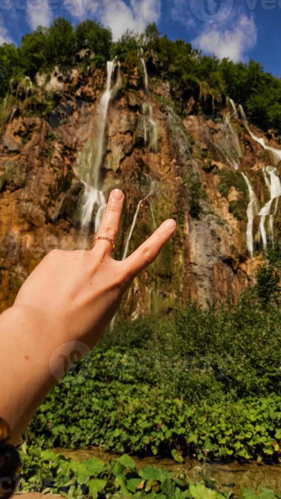 Tourist making victory sign at plitvice lakes national park in croatia photo