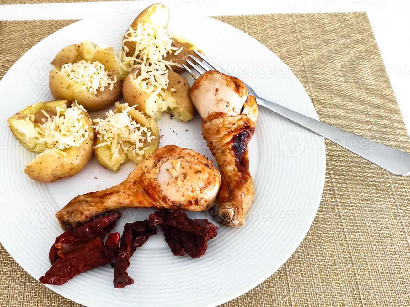 Deliciously arranged plate featuring baked potatoes, grilled chicken, and sun-dried tomatoes for a satisfying meal experience photo