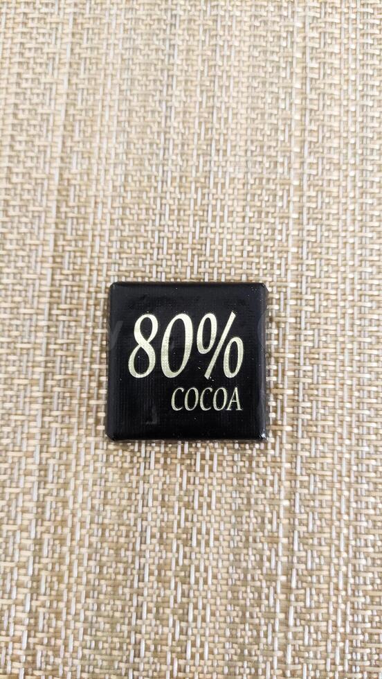 Dark chocolate square with 80 percent cocoa content displayed on textured surface highlighting gourmet indulgence photo
