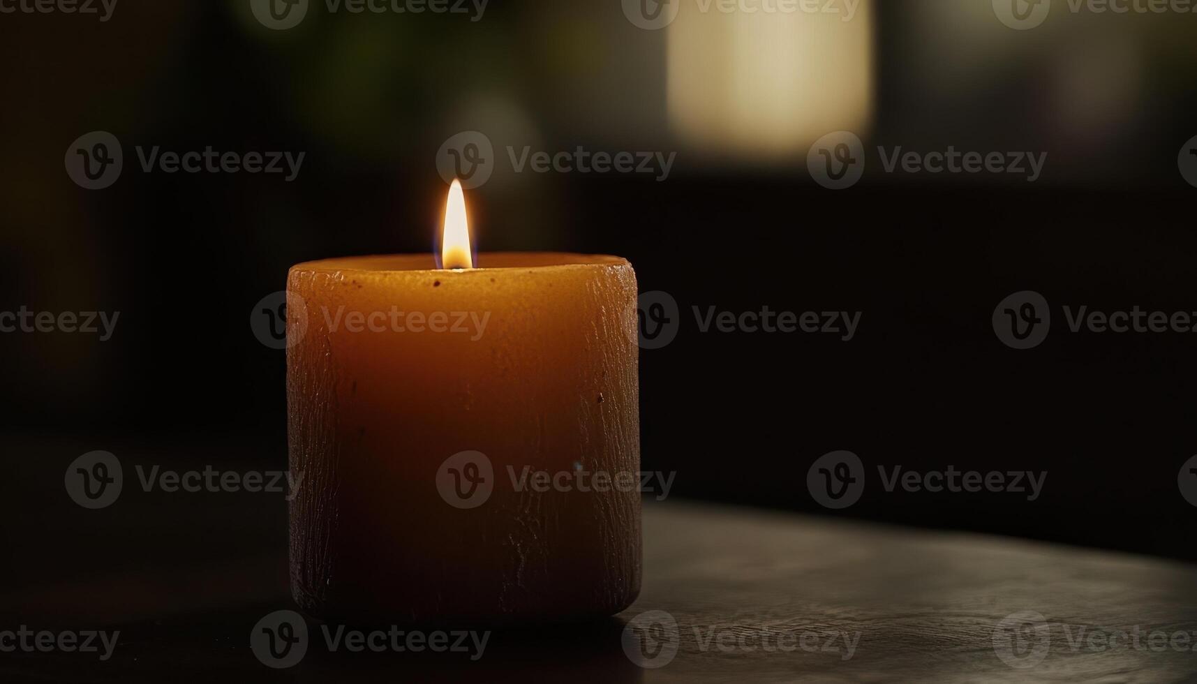 A single lit candle sits on a dark surface photo
