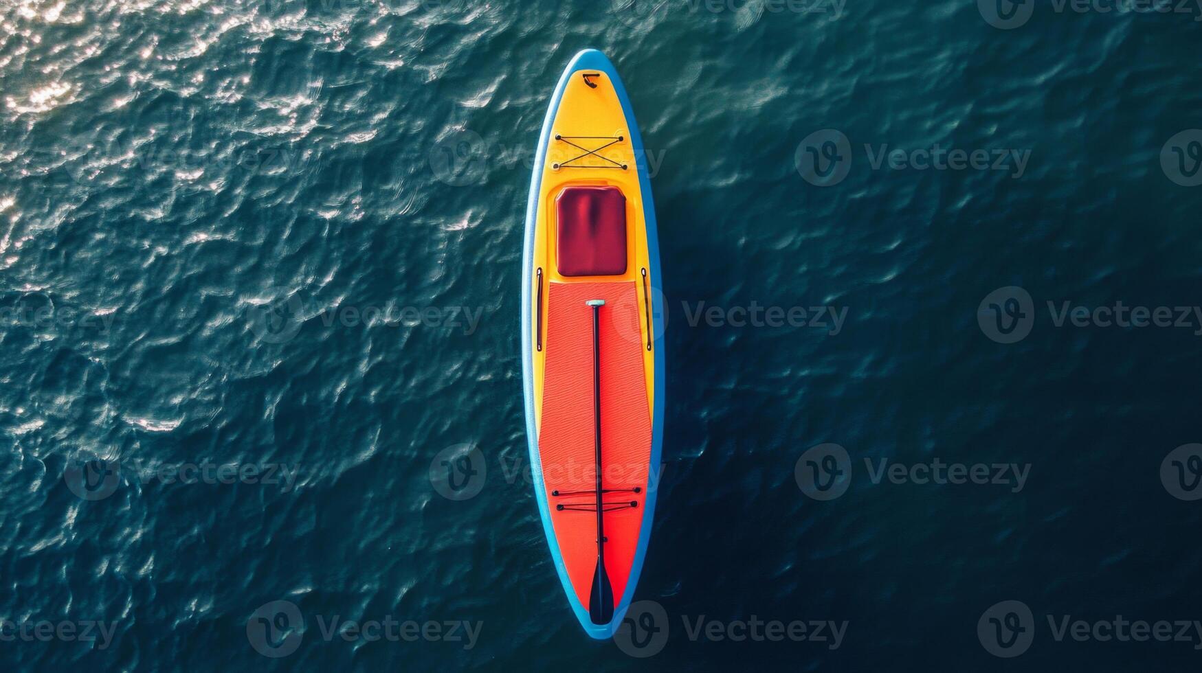 Aerial View of a Yellow and Red Paddleboard on Dark Blue Water photo