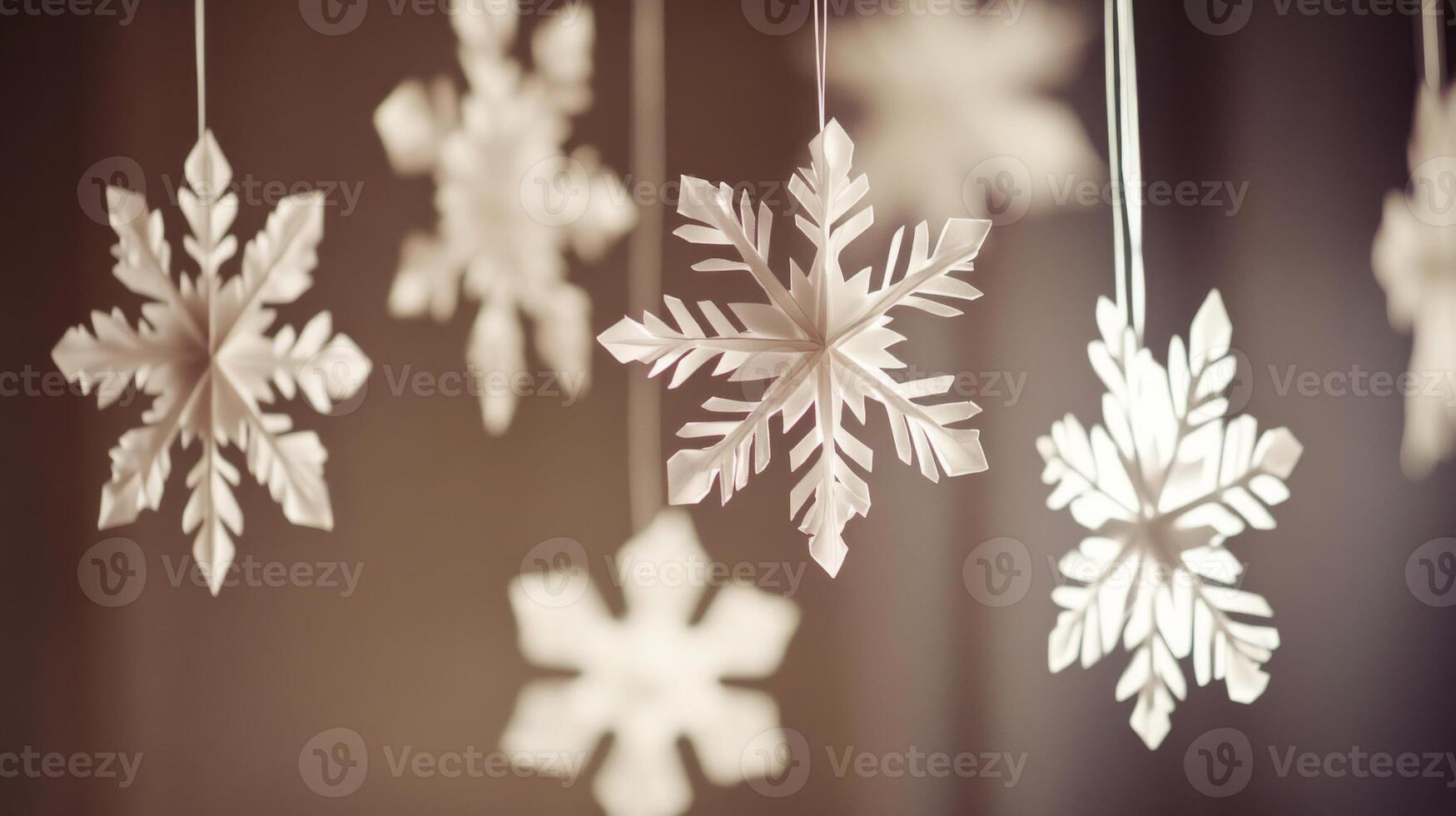 White Paper Snowflakes Hanging Against Brown Background photo