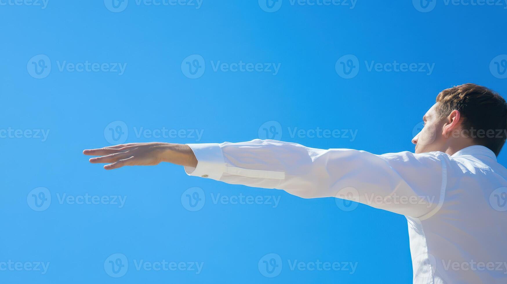 Man reaching out towards clear blue sky photo
