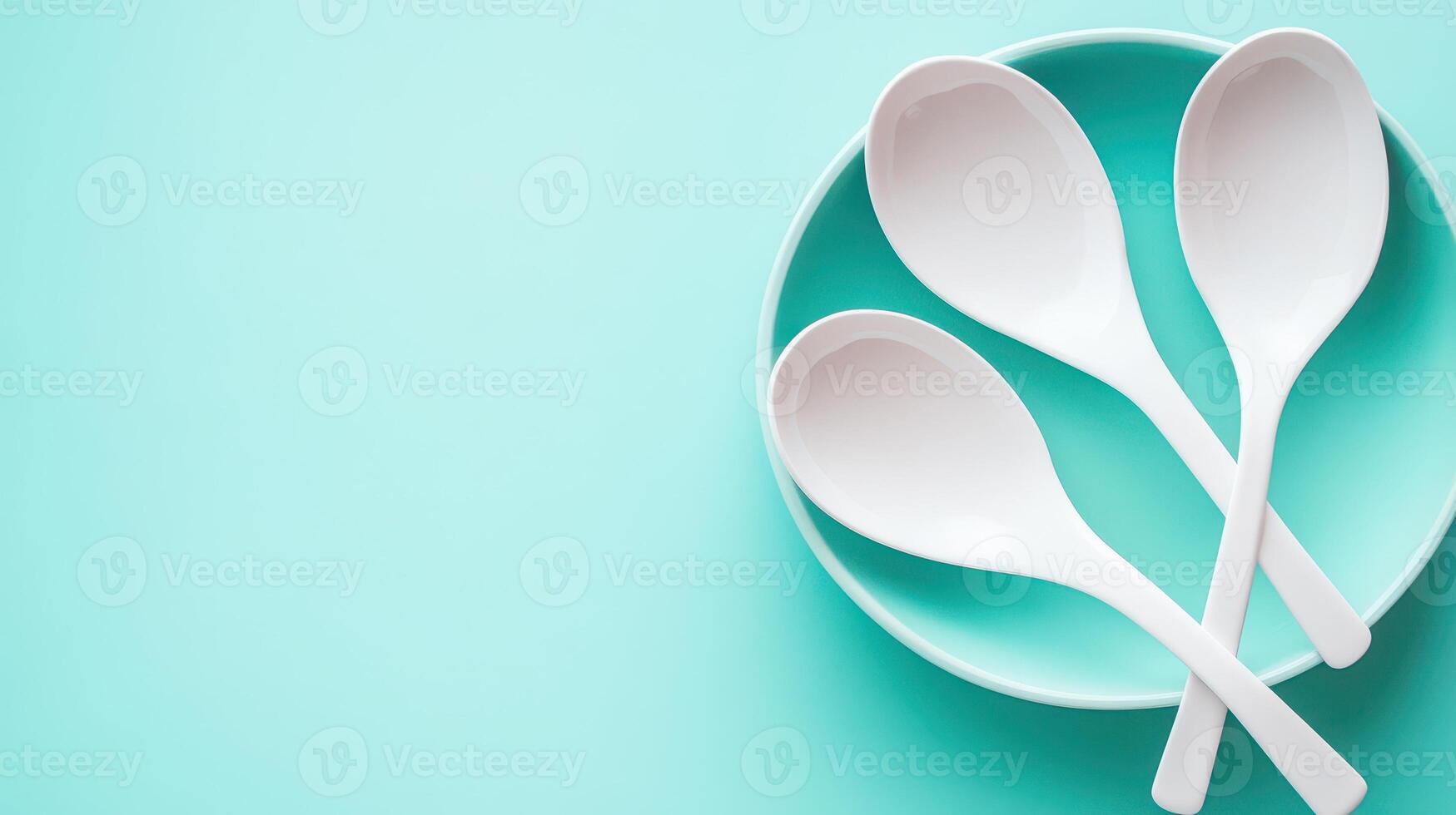 Three white spoons arranged on a turquoise plate photo