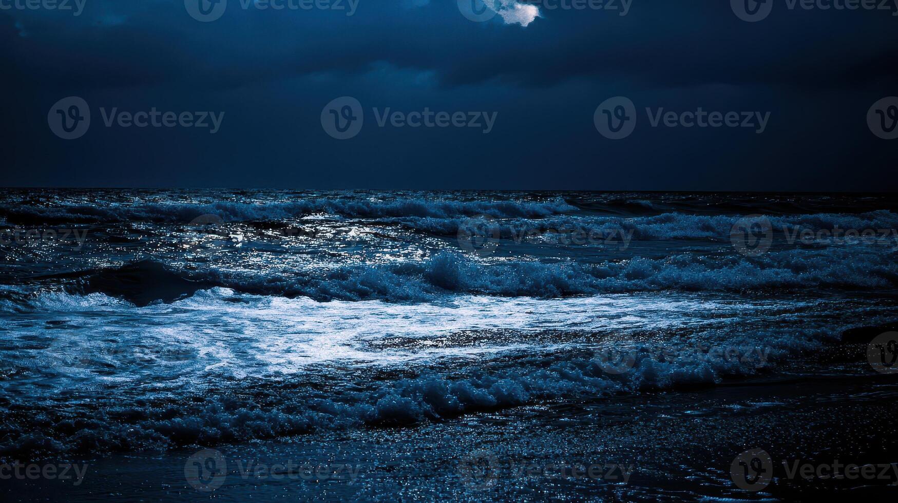 Waves crashing on a dark beach during nighttime photo