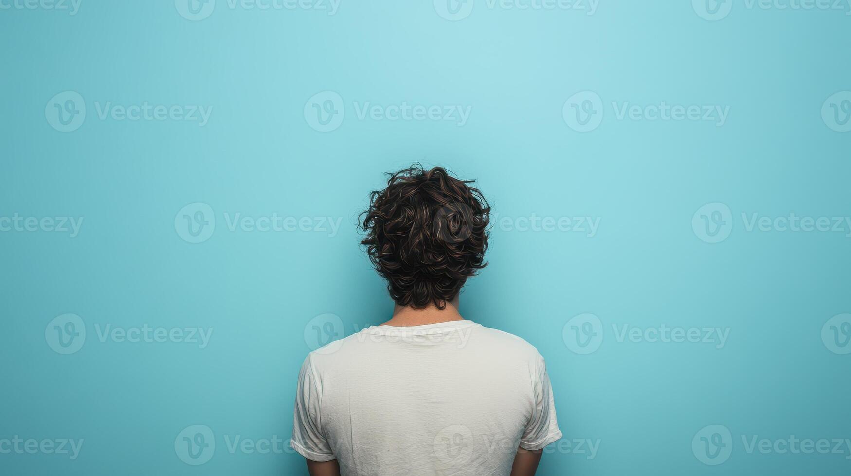 Individual facing blank blue wall with messy hair photo