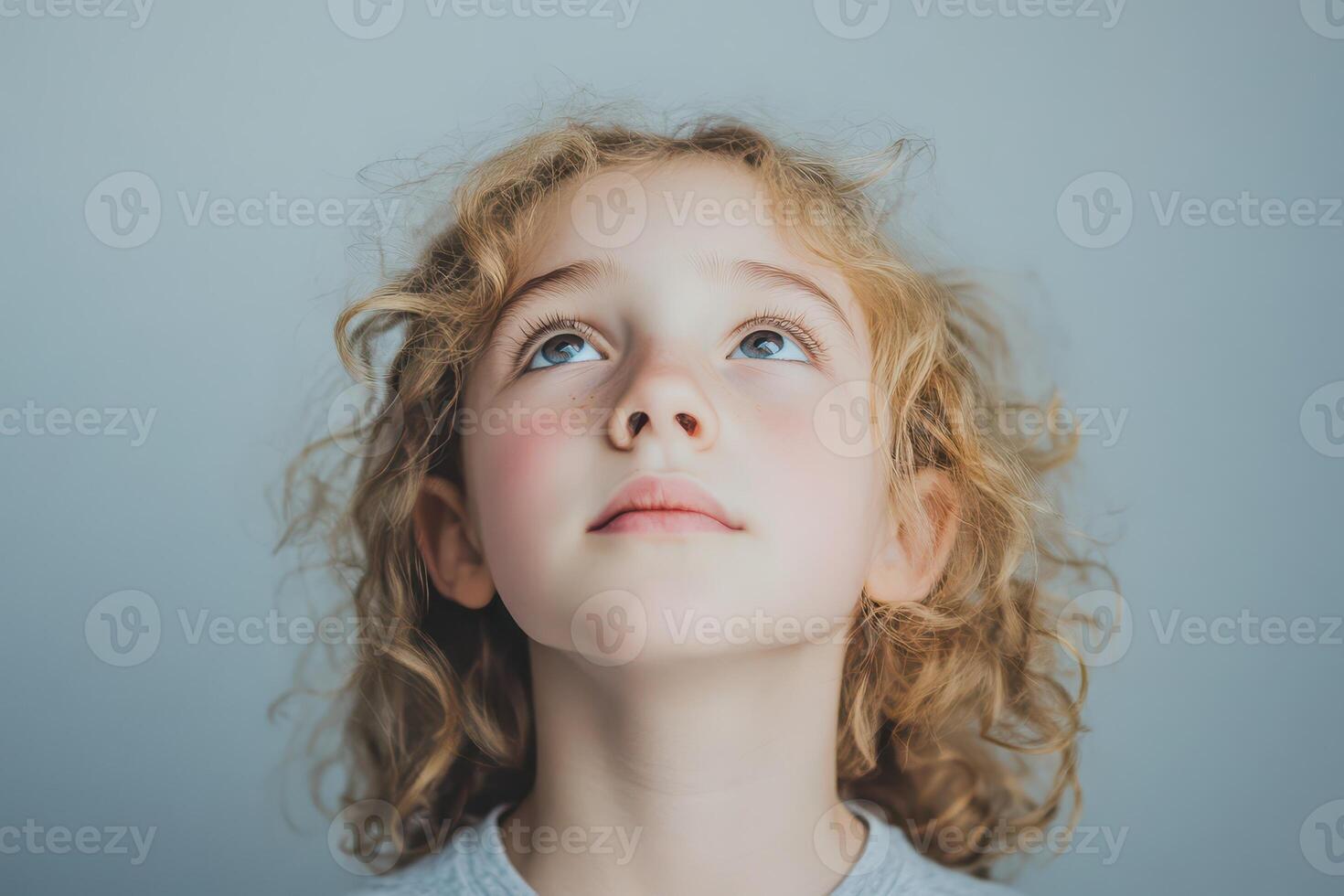 Child gazing upwards with curiosity in soft light photo