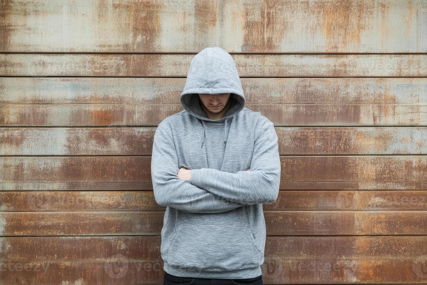 Man in gray hoodie stands against rusty wall photo