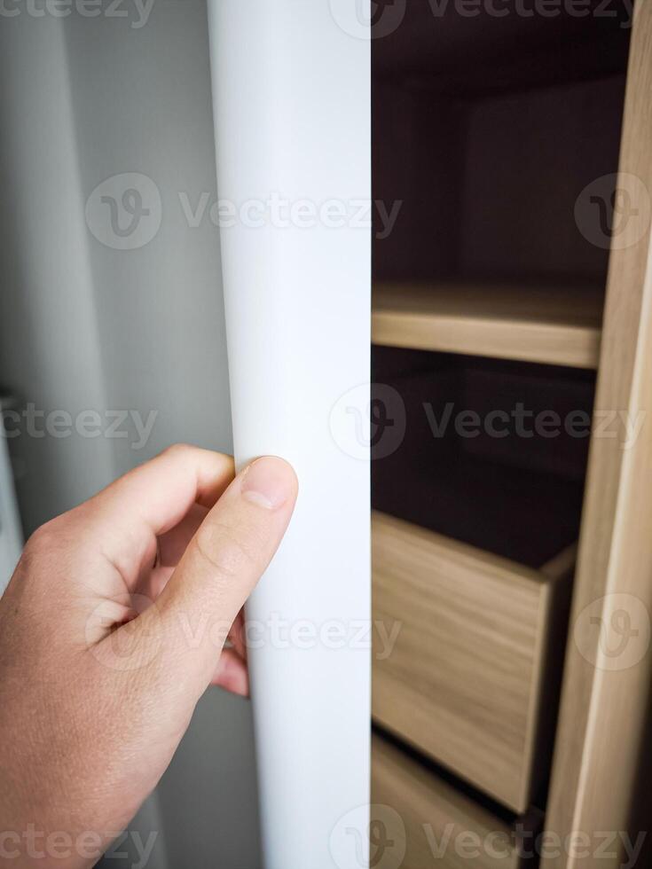 Modern bedroom wardrobe with sleek design showcasing open shelves and drawers, hand reaching for the door, stylish storage solution concept photo