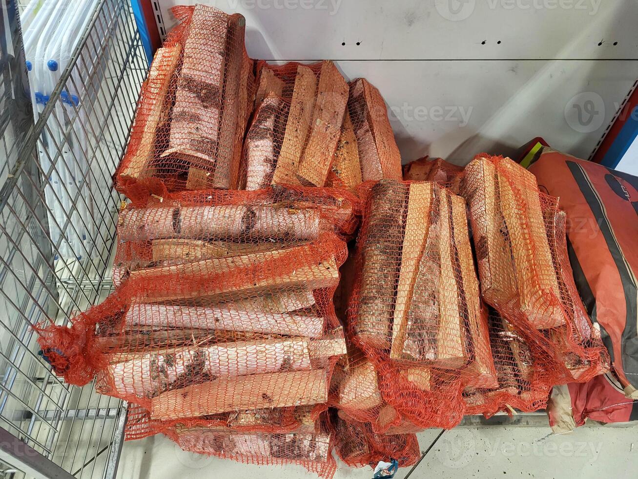 Birch logs, packed in a red nylon net, are sold in the store. photo