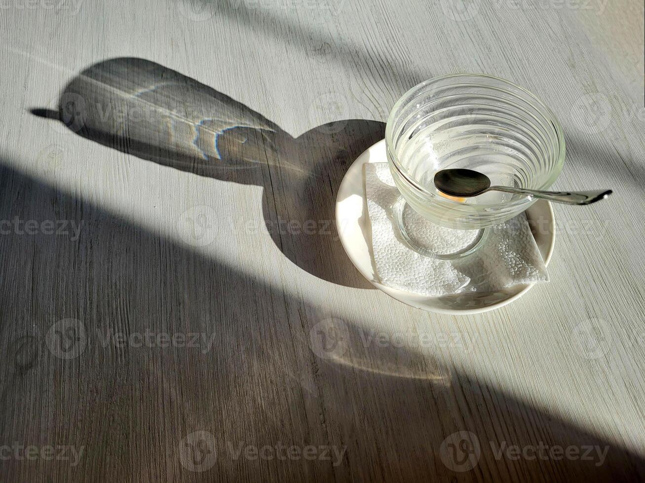 An empty ice cream bowl on the table with a spoon and shadows. View from above. photo