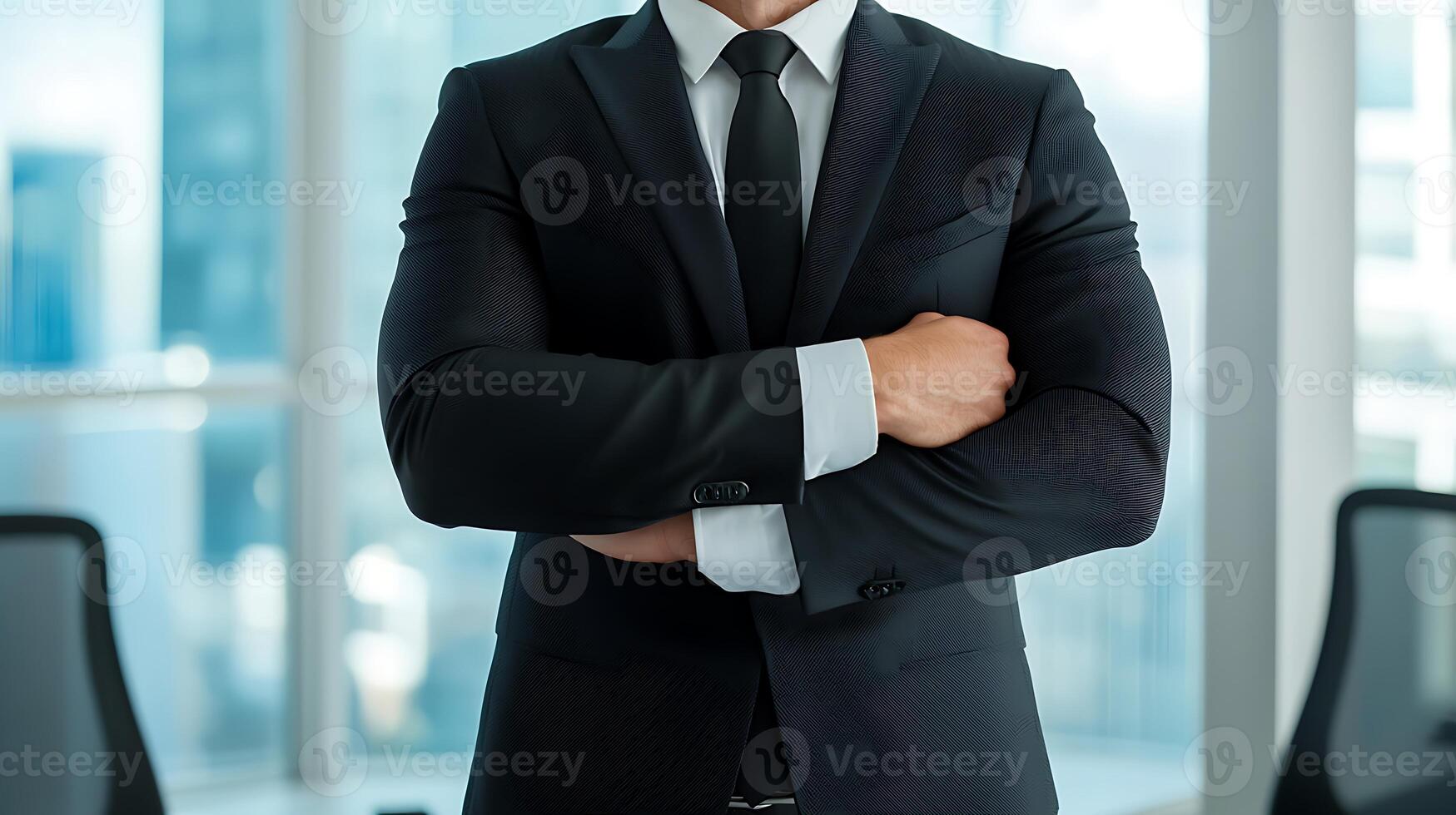 Confident businessman in a suit with arms crossed, standing in a modern office setting photo