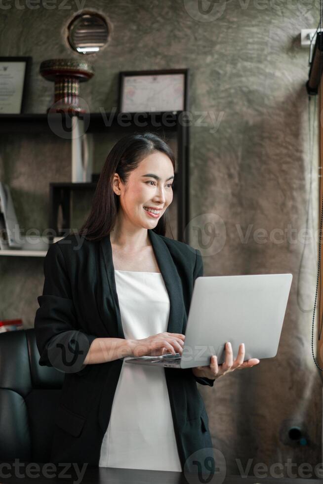 Confident businesswoman using a laptop in a contemporary office environment, showcasing productivity and professionalism. photo