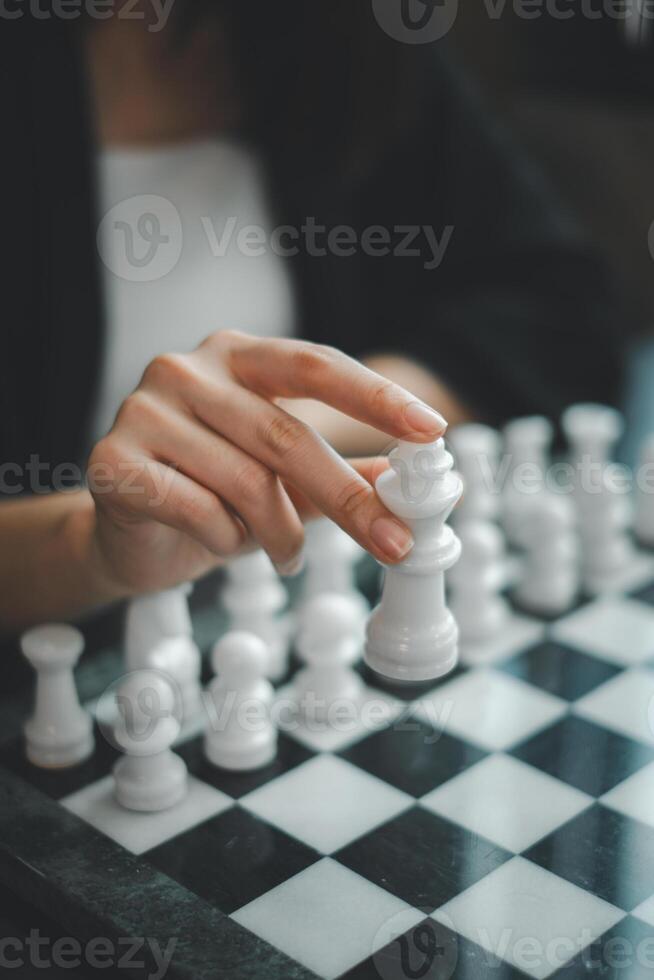 A focused hand moves a chess piece on a classic black and white chessboard, capturing the essence of strategic gameplay. photo