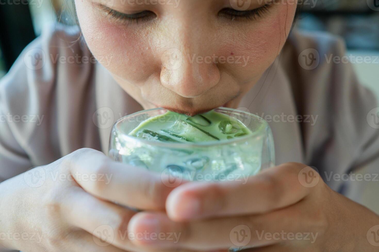 A person sipping a cool iced matcha latte, capturing the refreshing essence of a summer beverage. photo